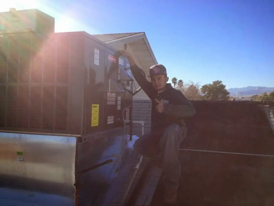 HVAC technician performing Heat Pump Repair on a rooftop unit in Talladega